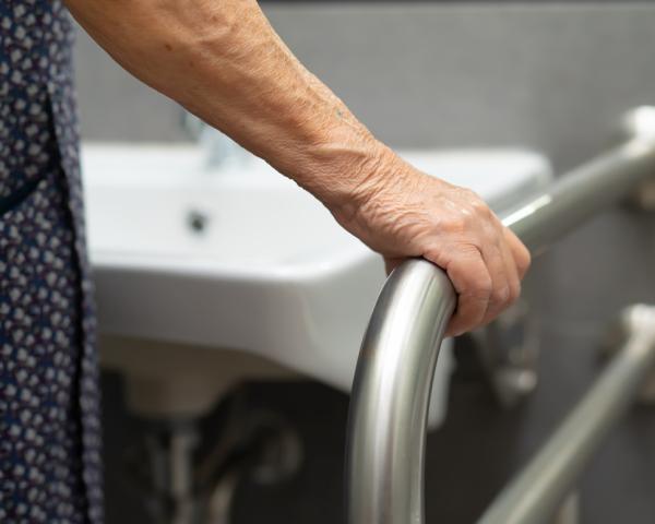 Ältere Hand am Badezimmergriff für Sicherheit.