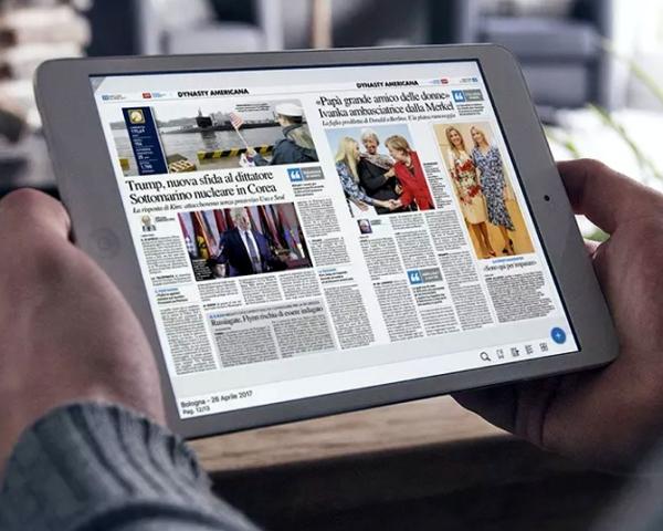 Person liest Zeitung auf einem Tablet in einem hellen Raum.