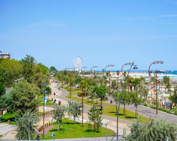 Promenade en bord de mer avec grande roue et plage.
