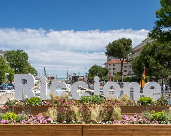 Riccione : station balnéaire avec canal, fleurs et ciel clair.