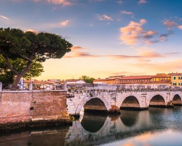 Pont historique sur rivière au coucher du soleil, paysage urbain pittoresque.